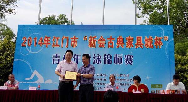 新會區體育局局長劉樹高給廣東新會古典家具城有限公司頒發“真情助競賽，愛心育棟梁”紀念牌匾 