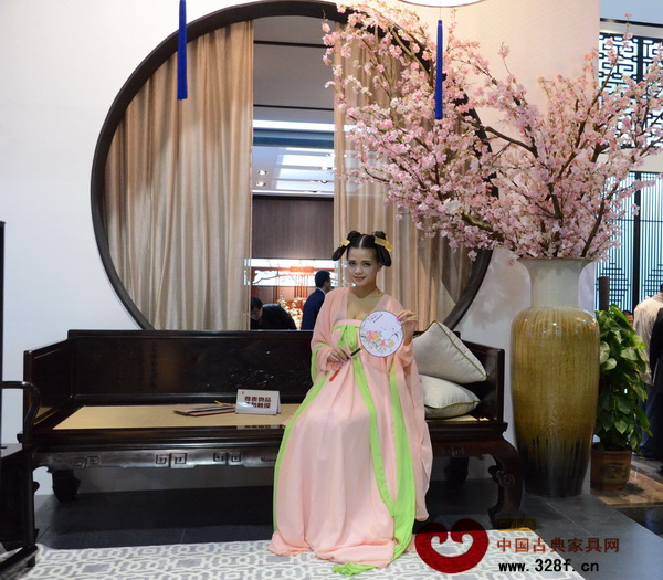 東莞名家具展的明堂紅木的展廳外，一位身穿漢服的古典美人笑意盈盈，相得益彰