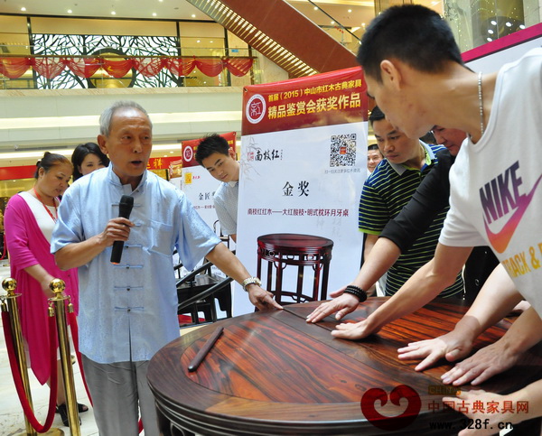 王秀林請(qǐng)消費(fèi)者觸摸“大紅酸枝·明式枕環(huán)月牙桌”平滑的桌面 