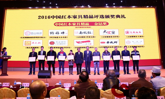 原故宮博物院文保科技部主任曹靜樓（右六），亞太地區(qū)手工藝大師馮文土（左六）共同為“金鉆獎(jiǎng)”獲獎(jiǎng)企業(yè)頒獎(jiǎng)，南枝紅紅木代表（右四）上臺(tái)領(lǐng)取證書