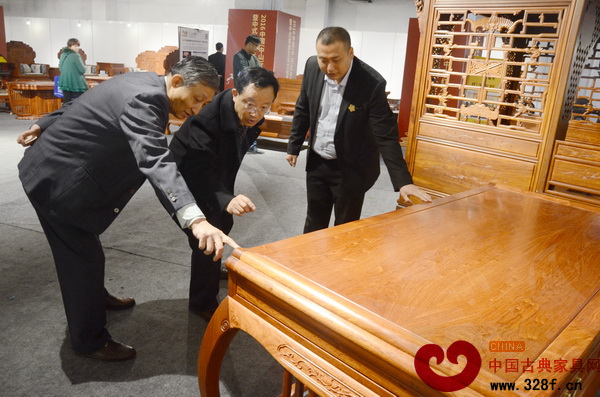 原故宮博物院文保科技部主任曹靜樓（左）、華南林業(yè)大學(xué)博士生導(dǎo)師李凱夫（中）對《緬甸花梨靈秀辦公臺》進(jìn)行細(xì)致的點(diǎn)評