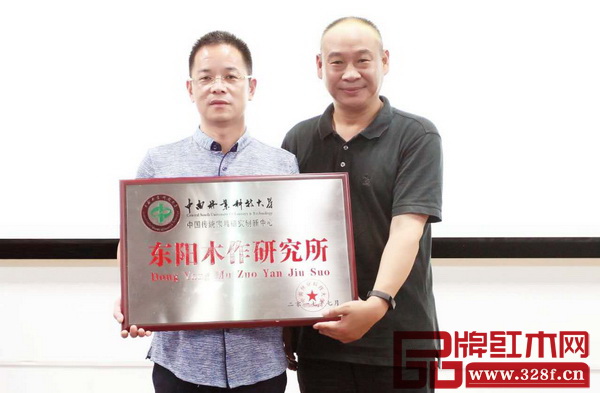 中南林業科技大學教授、家具學院院長劉文金（右）為純本森活董事長厲清平頒發“東陽木作研究所”牌匾