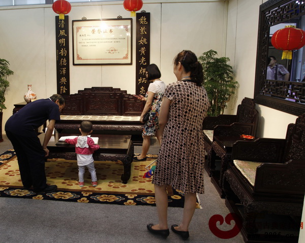 伍氏興隆展廳內，一名小孩在老人指導下翻閱紅木雜志