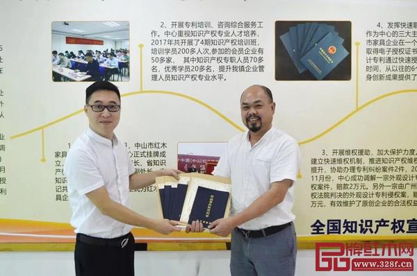  中山市紅木家具行業協會秘書長林毅昭（左）為陳正民頒發版權證書