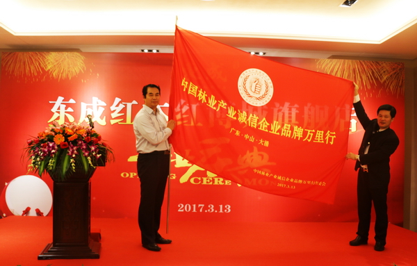 東成紅木董事長張錫復（右）從中國林產工業協會執行會長王滿（左）手中接過“中國林產誠信企業品牌萬里行”旗幟