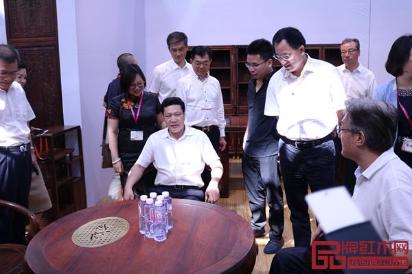 深圳市委常委、龍華區(qū)委書記余新國親身體驗孔連紅木展館現(xiàn)場的老撾大紅酸枝茶臺，并對孔連紅木的珍品給予了高度評價