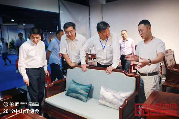 古木印象董事長(zhǎng)周洪根（右一）向前來參觀的領(lǐng)導(dǎo)、專家介紹古木印象產(chǎn)品的工藝及設(shè)計(jì)理念
