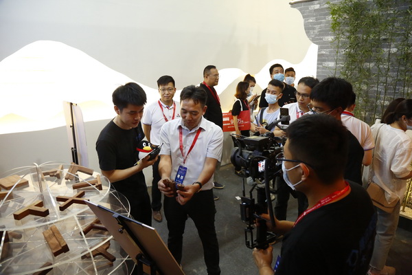  “中式原木整裝城市合伙人直播招募會”第一站在國方家居的建博會展位舉行，國方家居董事長陳新平（左三）介紹榫卯文化